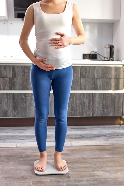Обрезанная беременная женщина проверяет вес дома каждое утро женщина смотрит, сколько она прибавила в весе