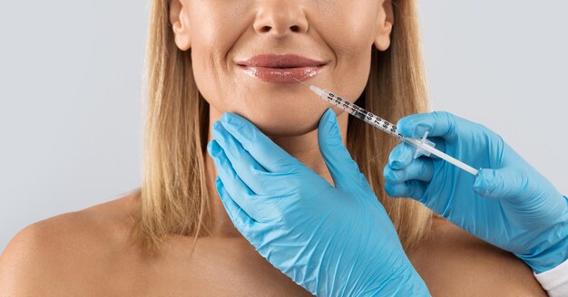 cropped of pretty middle aged woman getting lip filler