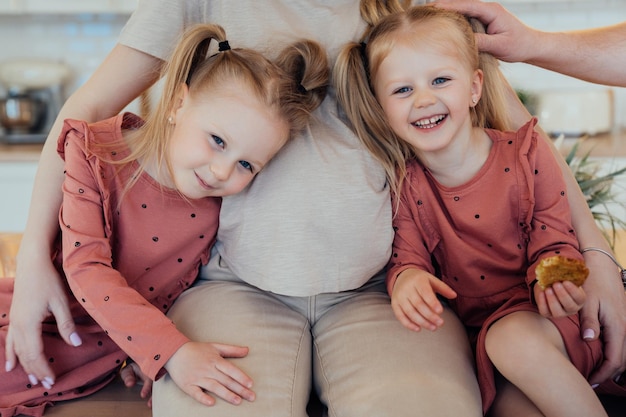 Cropped shoot of two little blonde girls with tails sitting with their pregnant mom happy family