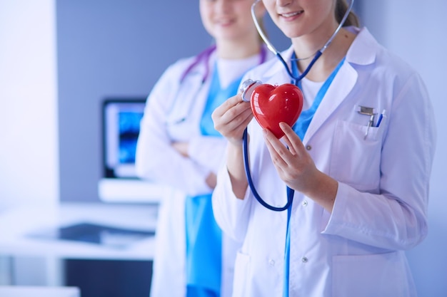 Cropped shoot of two young doctors female with stethoscope holding heart