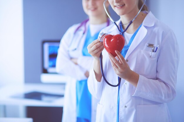 Cropped shoot of two young doctors female with stethoscope holding heart