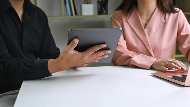 Cropped shot business team using digital table and discussing business data at office.