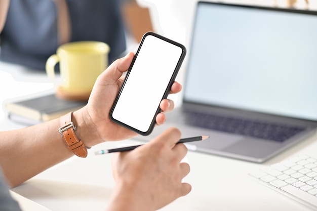 Cropped shot of businessman hand holding blank screen mobile phone at office