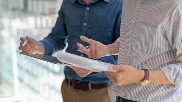 Colpo potato delle persone di affari che si consultano sul loro lavoro con l'archivio di documento e della compressa digitale