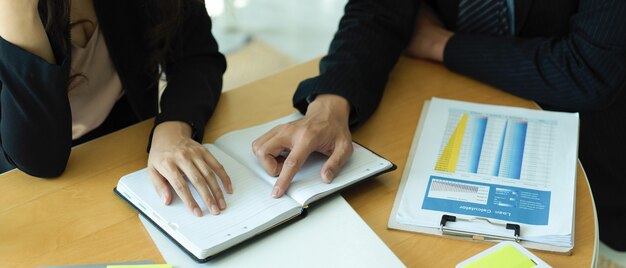 Cropped shot of businesspeople hands pointing on blank notebook while consulting on their project