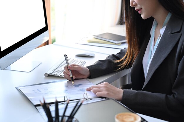 Cropped shot businesswoman analyzing financial reports at her office desk.