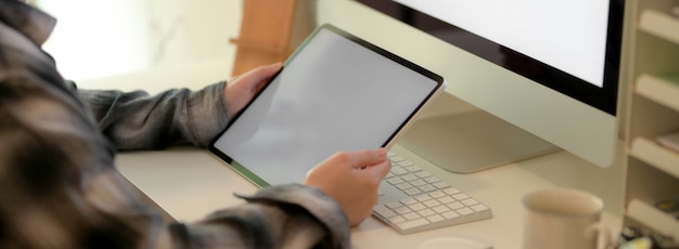 Cropped shot of businesswoman holding blank screen tablet while sitting at office desk