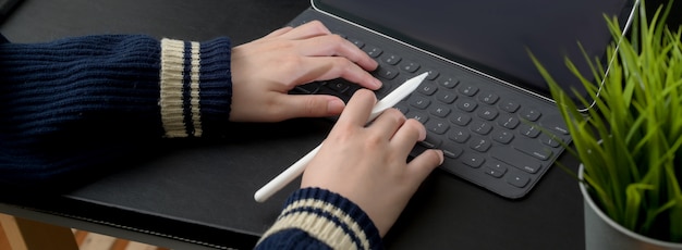 Cropped shot of businesswoman typing on digital tablet on black table