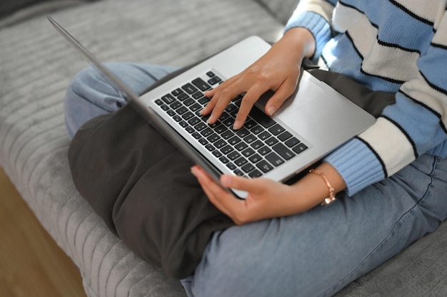 Cropped shot casual young woman browsing internet on laptop at home