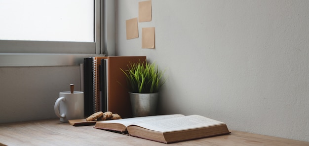 Foto colpo potato del posto di lavoro comodo con i libri e gli articoli per ufficio sulla tavola di legno