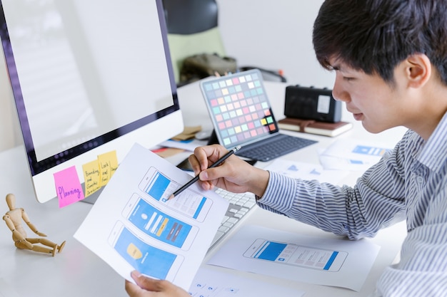 Cropped shot of creative ux ui designer developing programming and coding mobile application from prototype and wireframe layout. mobile application developer workplace concept