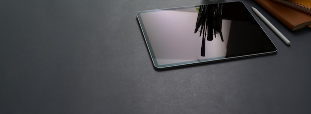 Photo cropped shot of dark concept office desk with digital tablet, stylus pen, office supplies and copy space