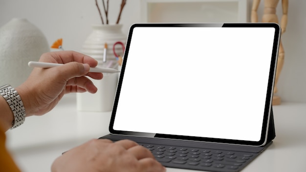 Cropped shot of designer using digital tablet with stylus pen on white table