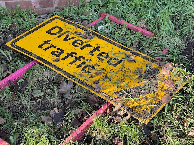 Cropped shot of diverted traffic sign thrown away in the grass covered in mud