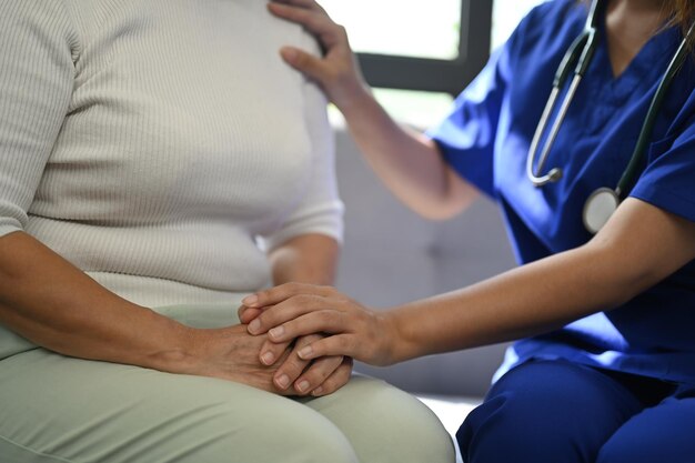 Cropped shot of doctor holding hands of senior patient for giving support empathy and understanding