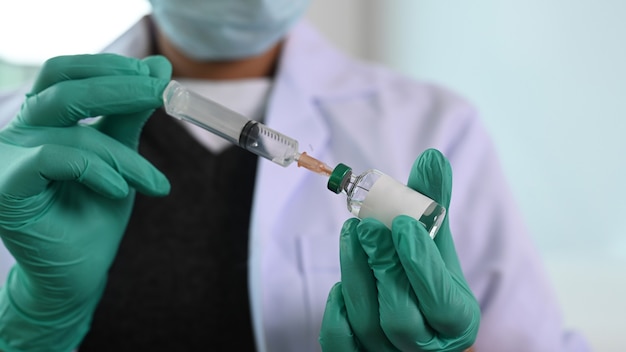 Cropped shot of doctor holding needle syringe and vaccine vial.