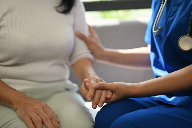 Cropped shot of doctor holding senior woman hand for hope and supporting Elderly healthcare concept