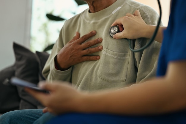 Photo cropped shot of doctor holding stethoscope checking heart and lungs of elderly male patient