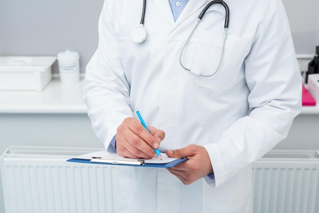 Cropped shot of doctor writing in clipboard