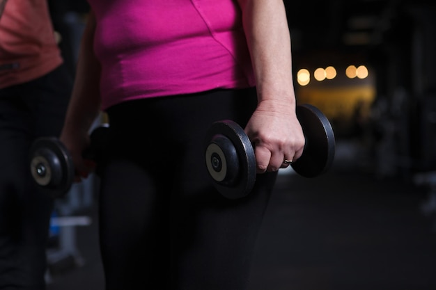 Cropped shot of dumbbells in the hands of a senior woman exercising at the gym