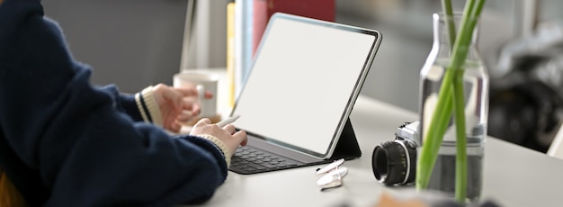 흰색 작업 테이블에 디지털 태블릿에 입력하는 여성 대학생의 자른 샷