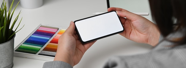 Cropped shot of female designer looking for information on mock-up smartphone