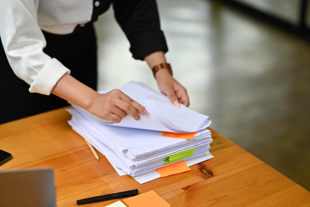 Cropped shot of female employee woman working on stack documents at her office desk