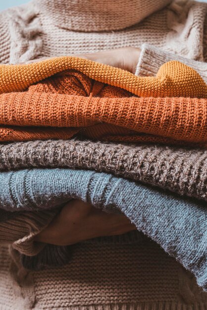 Photo cropped shot of a female holding knitted warming sweaters preparing clothes for coming cold season