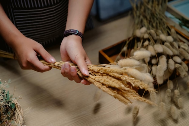 Cropped shot of florist making a bouquet of dried flowers at her workstation Small business concept