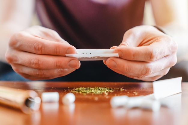 Cropped shot front view of young man making marijuana joint