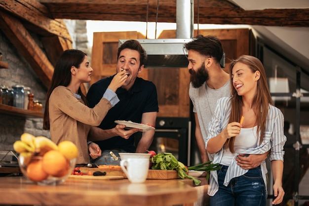 Ritagliata di un gruppo di amici che assaggiano il cibo dopo la cottura