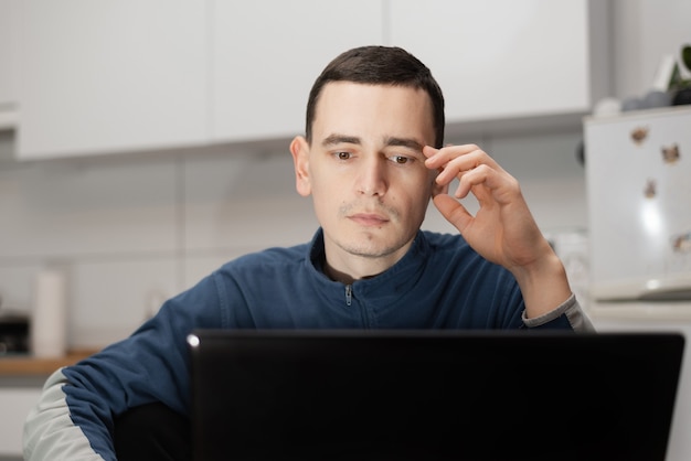 Cropped shot of a handsome young businessman sitting alone at home and using his laptop