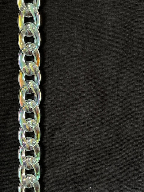 Cropped shot of irridescent plastic chain on black background