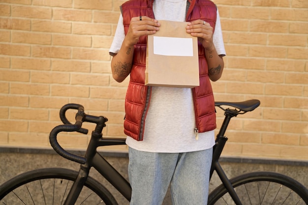 Photo cropped shot of a male courier holding paper bag with food from