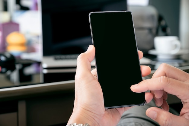 Cropped shot of man hands using mobile phone while working at office.