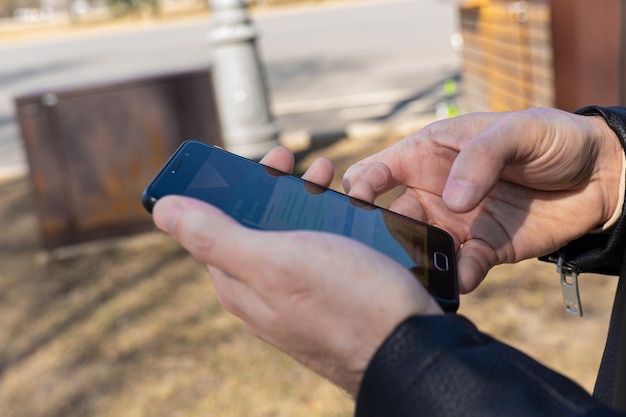 A cropped shot of a man's hands holding a smartphone reading a text message on a cell phone during