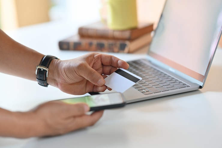 Photo cropped shot of man using mobile phone and credit card for online payment.