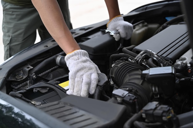 Cropped shot mechanics working on car engine in mechanics garage