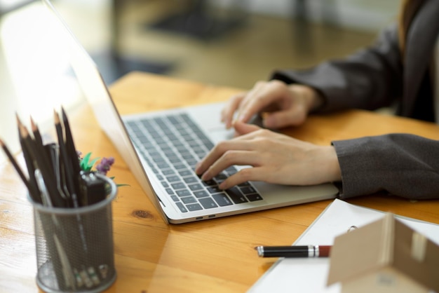 Cropped shot of millennial businesswoman or female employee working on laptop computer, typing on keyboard.