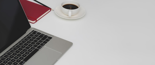 Cropped shot of minimal workspace with laptop, stationery, coffee cup and copy space