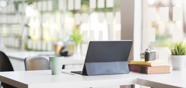 Cropped shot of modern office room with blank screen tablet, camera and office supplies