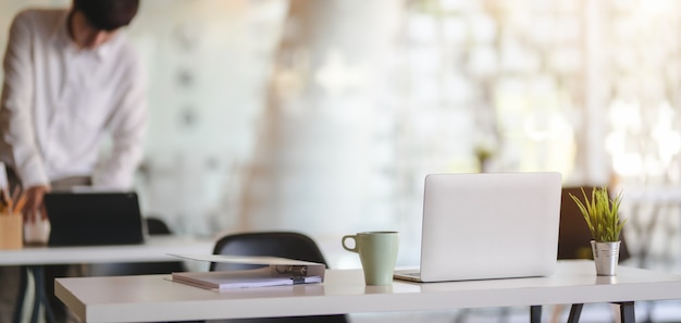 Cropped shot of modern office room with laptop computer and office supplies with office environment background