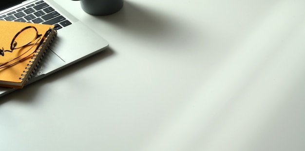 Cropped shot of modern workplace wit laptop computer, books and office supplies with copy space on white desk 