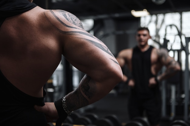 Cropped shot of a muscular bodybuilder posing in front of the mirror