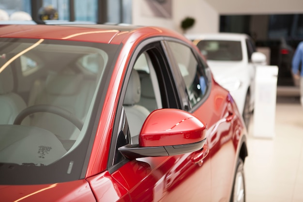 Cropped shot of a new shiny red automobile on sale at car dealership.