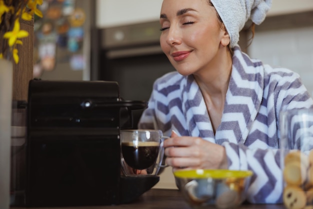 写真 自宅のキッチンでコーヒーを淹れ、おいしいコーヒーの香りを楽しむ女性のトリミングショット。