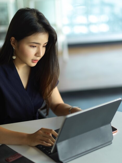 オフィスルームでデジタルタブレットを使った仕事に焦点を当てた女性サラリーマンのクロップドショット