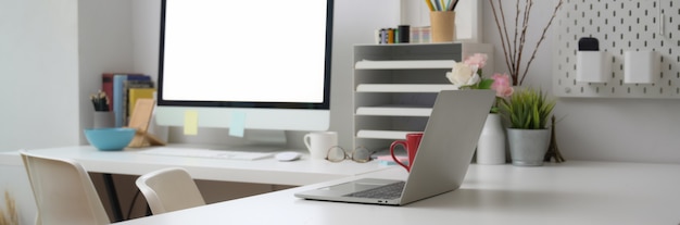 Cropped shot of office desk with blank screen computer on white table