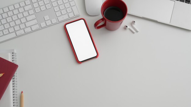 Cropped shot of office room with blank screen phone and office supplies on white table