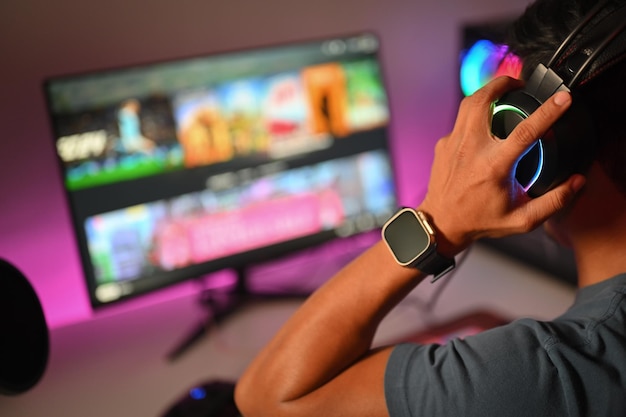 Cropped shot pro gamer wearing headset playing online video game on his personal computer at home